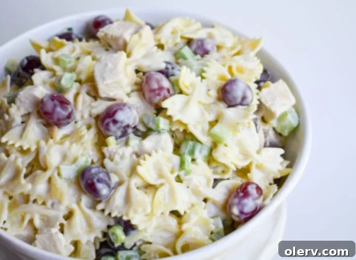 Bright Lemon Tarragon Pasta Medley 2 A vibrant bowl of Lemon Tarragon Pasta Salad, showcasing bowtie pasta, red grapes, chicken, and fresh tarragon leaves.