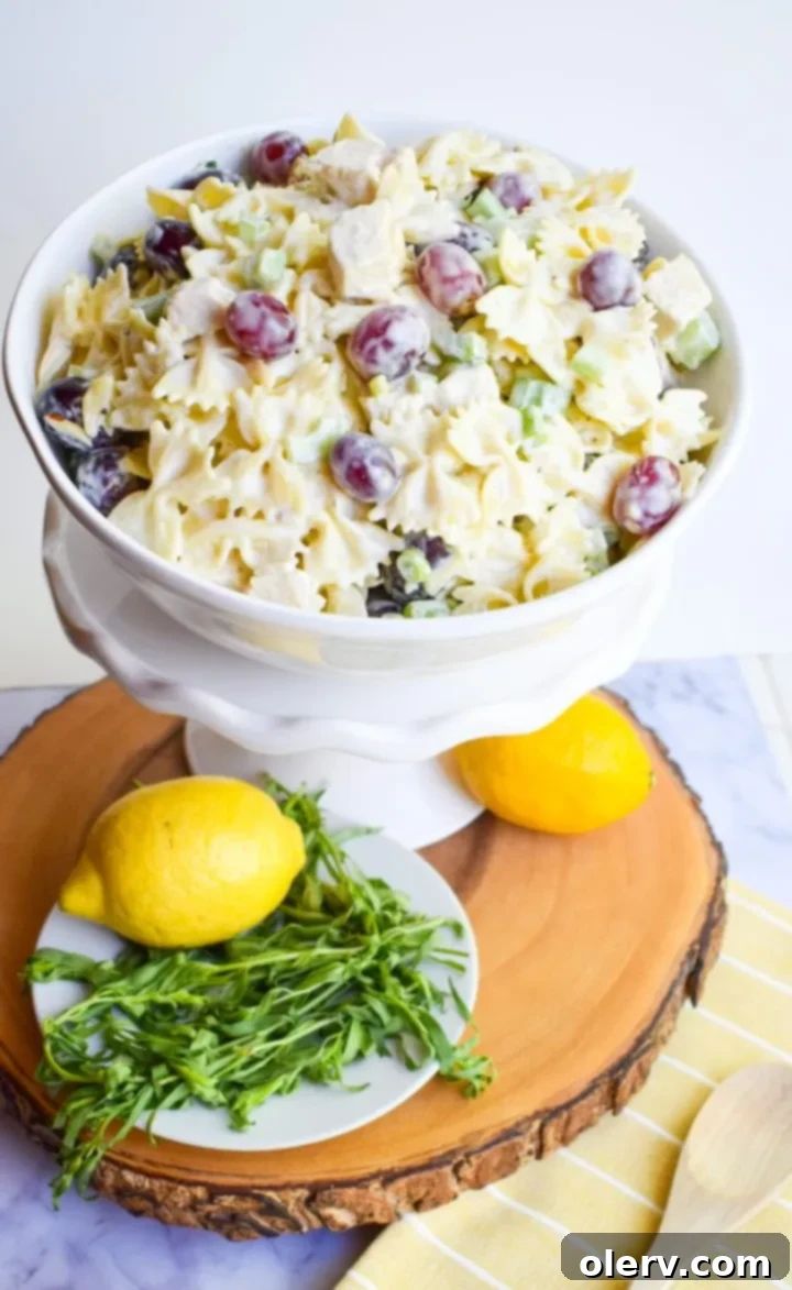 Bright Lemon Tarragon Pasta Medley 4 Ingredients for Lemon Tarragon Pasta Salad laid out, including fresh tarragon, lemons, grapes, chicken, and pasta.