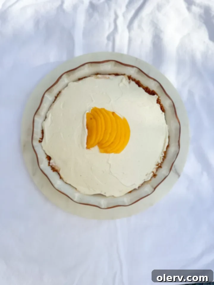 Creamy No-Bake Peach Delight 6 A slice of no-bake peach cream pie garnished with fresh mint, sitting on a white plate.