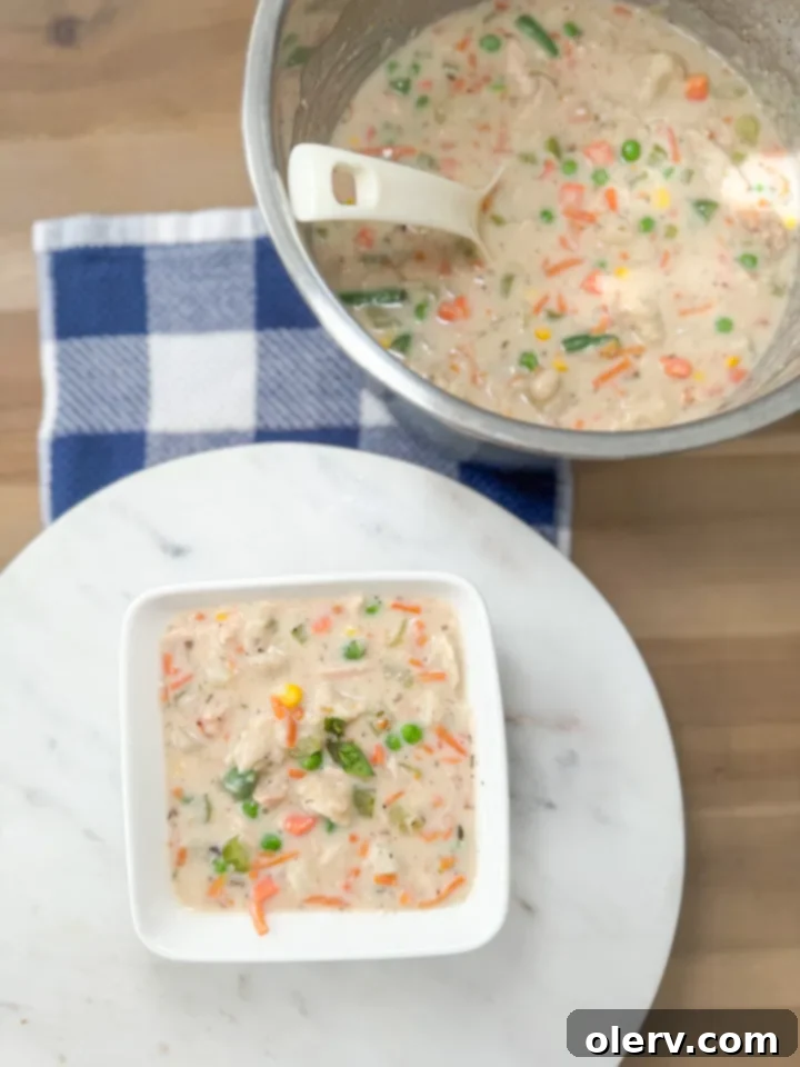 A close-up view of the ingredients for Instant Pot Chicken and Dumplings, including diced vegetables, shredded chicken, and uncooked biscuit dough cubes.