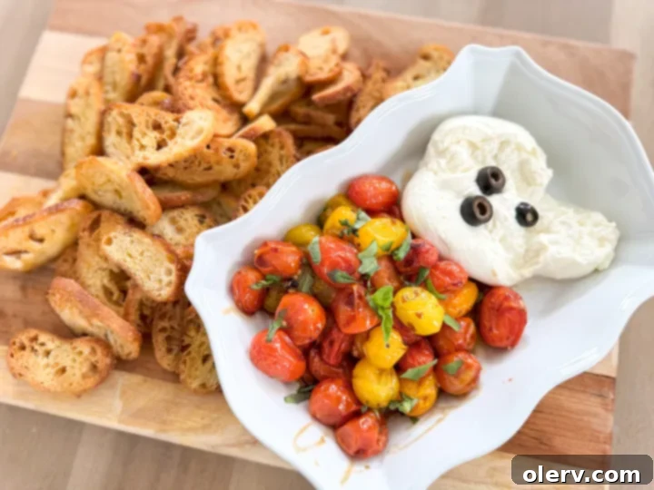 Burrata and Bruschetta Dip 4 The Boo-rata Dip from a wider angle, showing the ghost-shaped burrata with olive features surrounded by roasted cherry tomatoes and fresh basil.