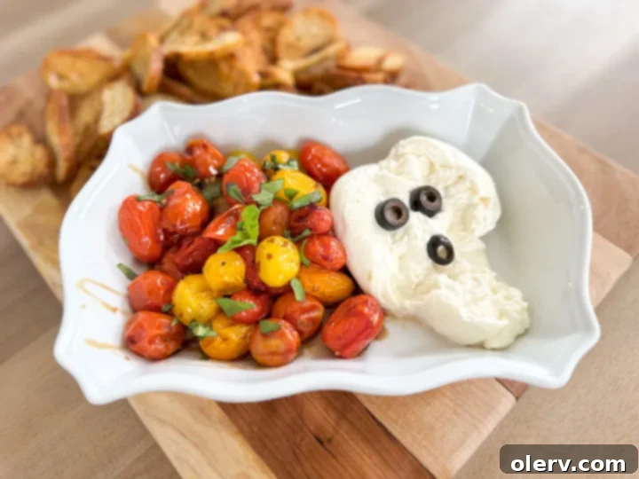 Burrata and Bruschetta Dip 5 A close-up of a spoon scooping creamy burrata and roasted tomatoes onto a crostini.