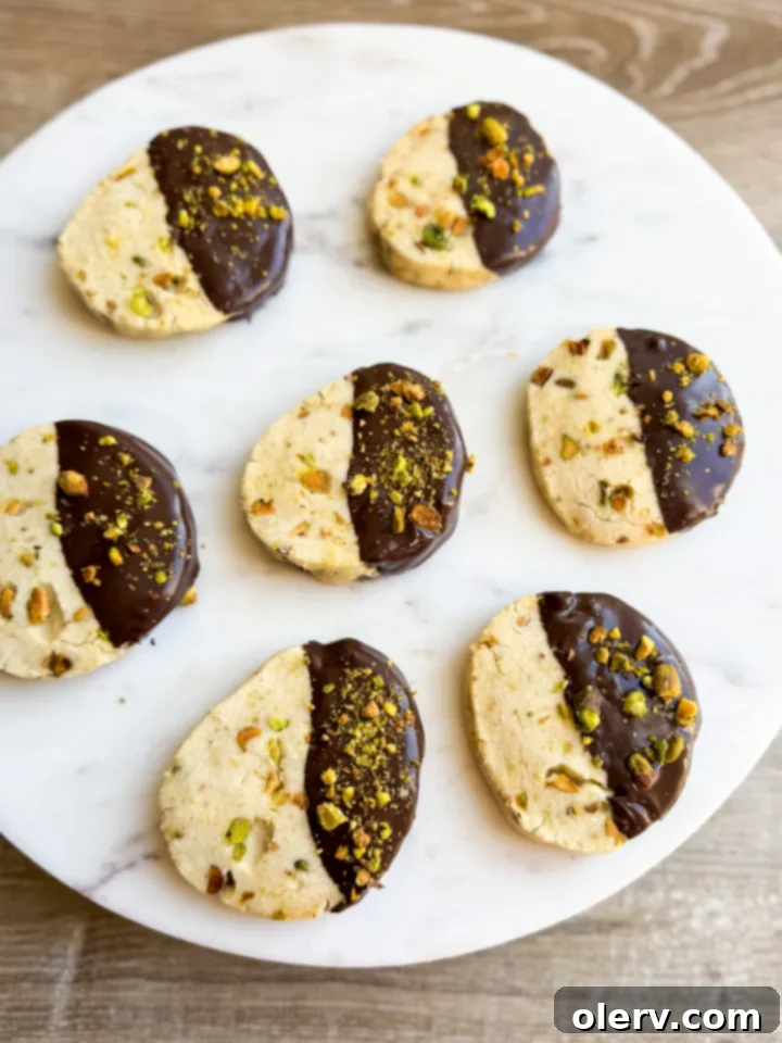 Buttery Pistachio Shortbread Cookies 6 Stacked pistachio shortbread cookies with chocolate on a white plate, ready to be served.