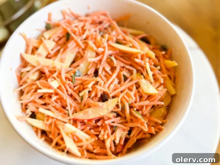 Vibrant Carrot Slaw 4 Hands mixing the Carrot Slaw Salad with Maple Dijon dressing in a large bowl.