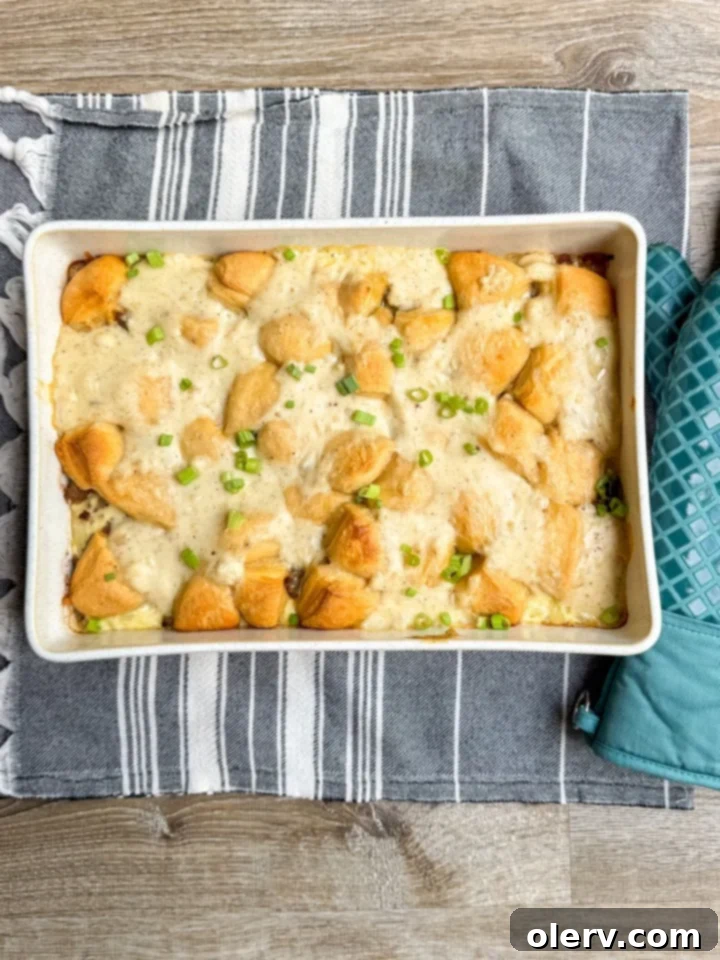 Hearty Biscuits and Gravy Bake 5 Homemade white gravy being stirred in a skillet, showing its creamy texture.