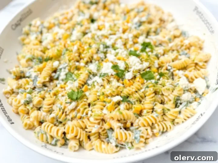 Creamy Street Corn Pasta Salad 5 A large bowl filled with cooked pasta, roasted corn, diced jalapeños, and green onions, ready for the dressing.