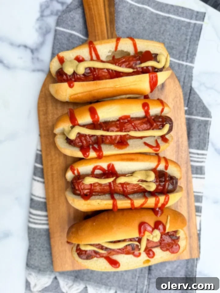 Crispy Air Fryer Hot Dogs 3 Two cooked hot dogs resting in their buns, garnished with classic condiments.
