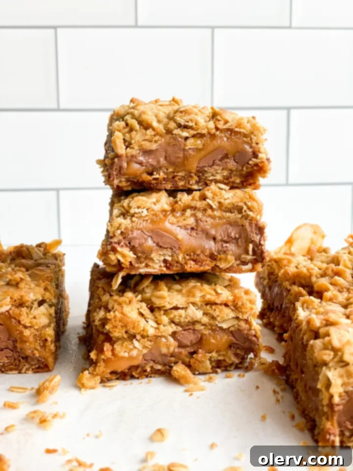 Unforgettable Carmelita Bars 2 Delicious homemade Carmelitas bars stacked on a white plate, showcasing layers of oat crust, gooey caramel, and melted chocolate.