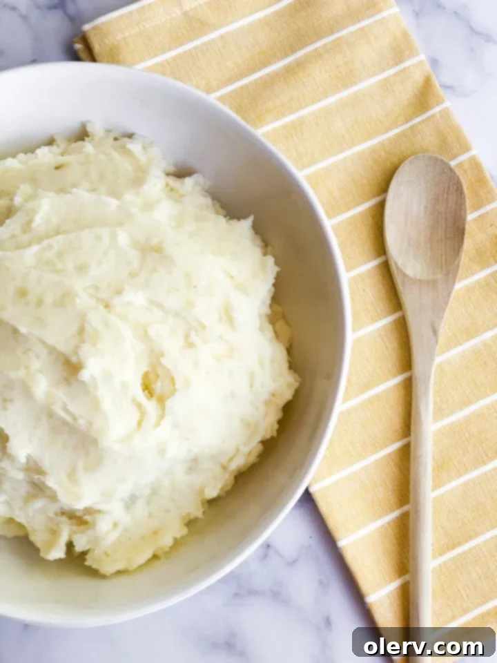 Fluffy Instant Pot Mashed Potatoes in Minutes 5 Instant Pot Mashed Potatoes served in a white bowl with a side of green beans.