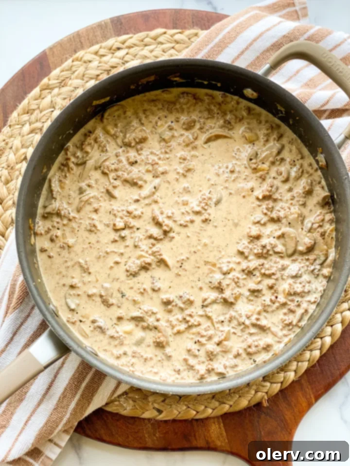 The Ultimate Creamy Beef & Mushroom Stroganoff 3 Close-up of savory ground meat and mushroom mixture cooking in a pan for stroganoff
