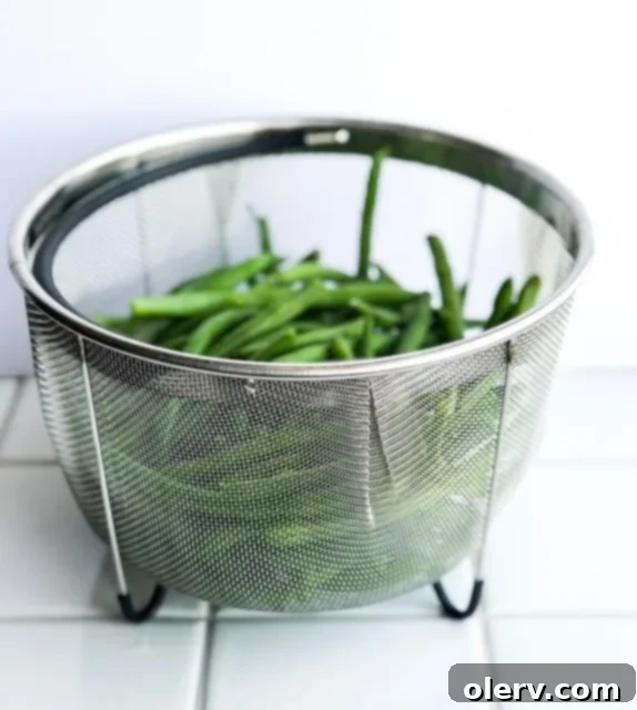 Quick Instant Pot Garlic Green Beans 4 Instant Pot Garlic Green Beans being lifted from the pressure cooker in a steam basket