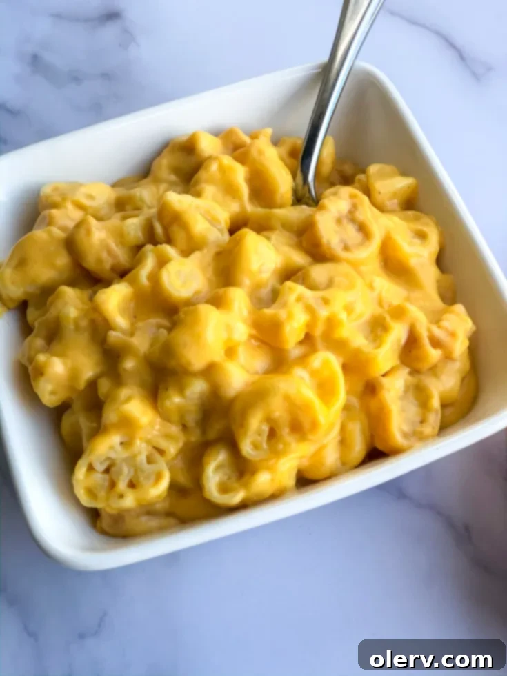 Autumn Pumpkin Macaroni Bake 7 A serving of Spiced Pumpkin Mac & Cheese, with a spoon ready to scoop, highlighting its creamy, inviting texture.