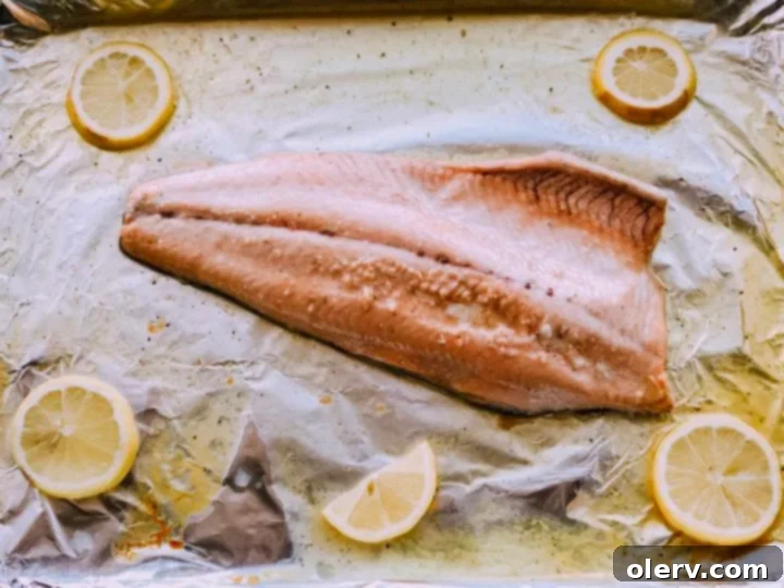 Golden Honey Garlic Glazed Salmon 2 Close-up of golden-brown honey garlic salmon fillet on a baking sheet, garnished with fresh herbs