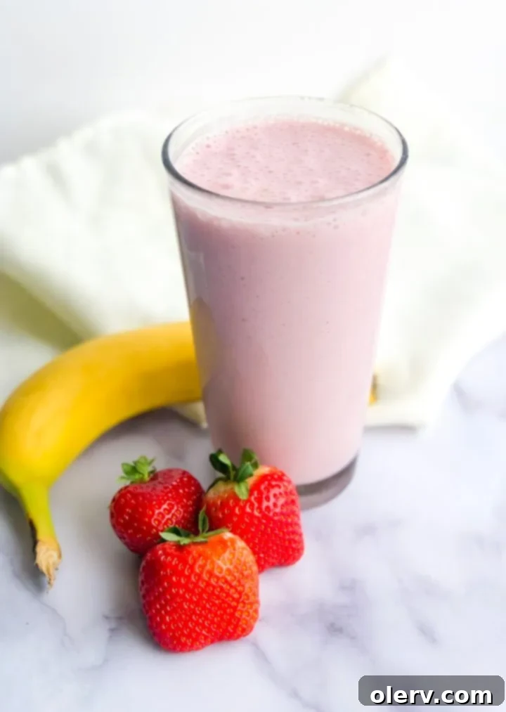 Strawberry Banana Bliss 2 Freshly blended strawberry banana protein smoothie in a glass, garnished with a strawberry slice.