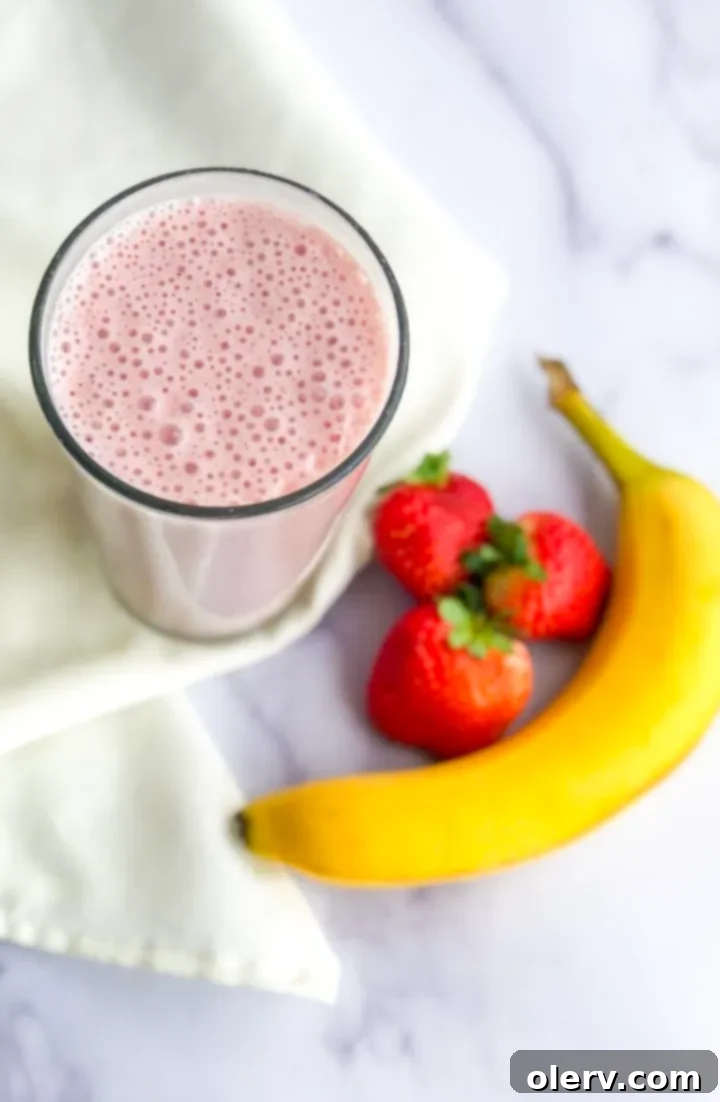 Strawberry Banana Bliss 5 A scoop of protein powder being added to a blender with other smoothie ingredients.