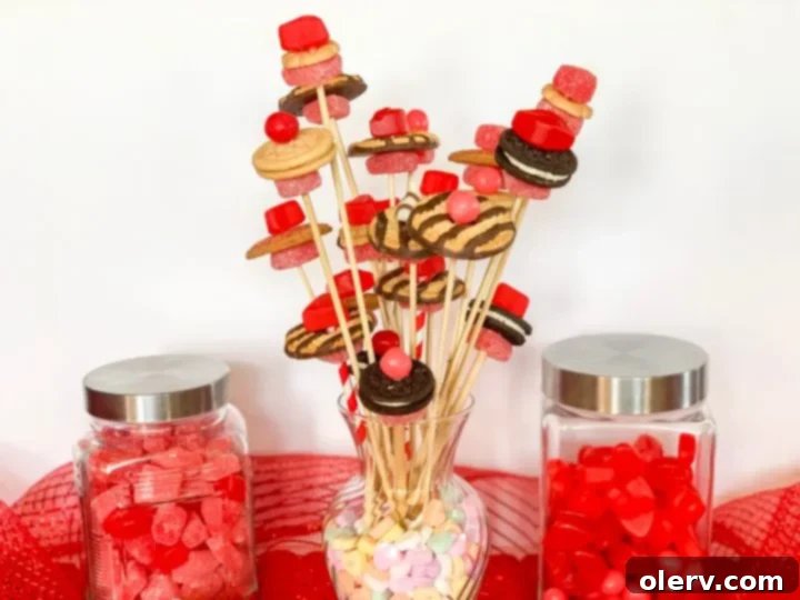 Valentine's Sweetest Blooms 3 Close-up of a festive Valentine's Candy Flower Bouquet showcasing various cookies and heart-shaped candies on skewers, set against a blurred background.