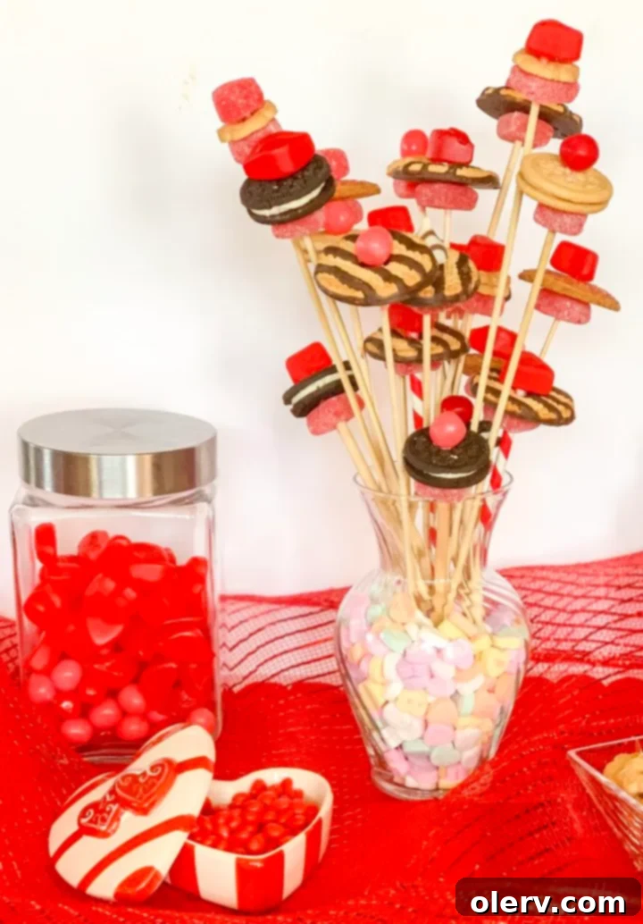 Valentine's Sweetest Blooms 4 A hand holding a partially assembled candy flower, showing a cookie and a cinnamon square on a skewer, with other candy ingredients nearby.