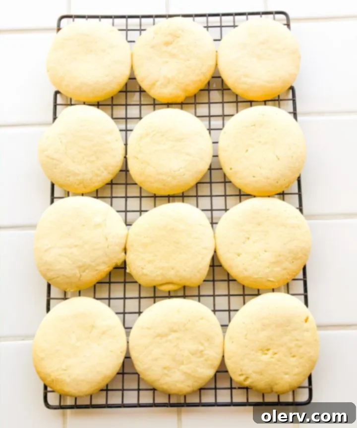 Tender Sour Cream Sugar Cookies 8 A bowl of creamy, white frosting with a whisk, ready to be applied to the cooled cookies.