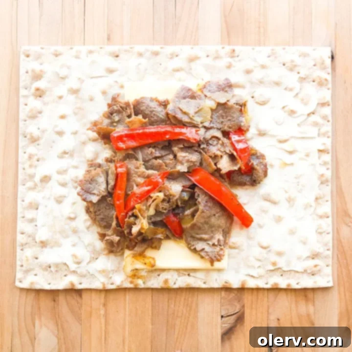 Philly Cheesesteak Crunchwrap 6 Philly Cheesesteak filling, including steak, peppers, onions, and cheese slices, neatly piled in the center of a lavash wrap