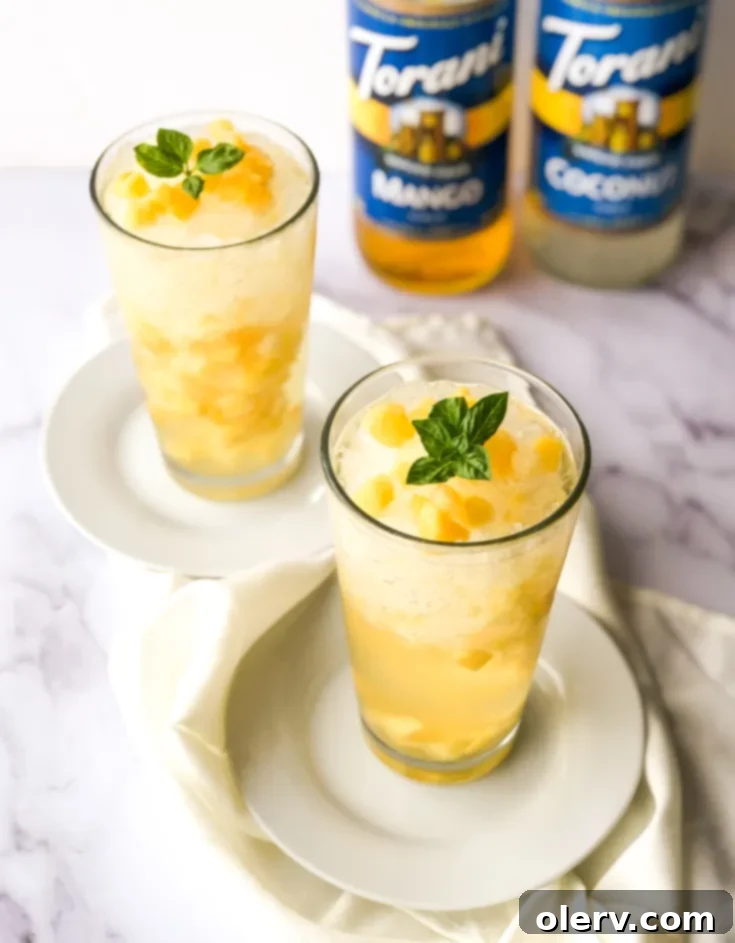Virgin Tropical Mango Mojito 9 A vibrant Tropical Mango Mojito Mocktail in a tall glass, garnished with fresh mint and a lime slice.