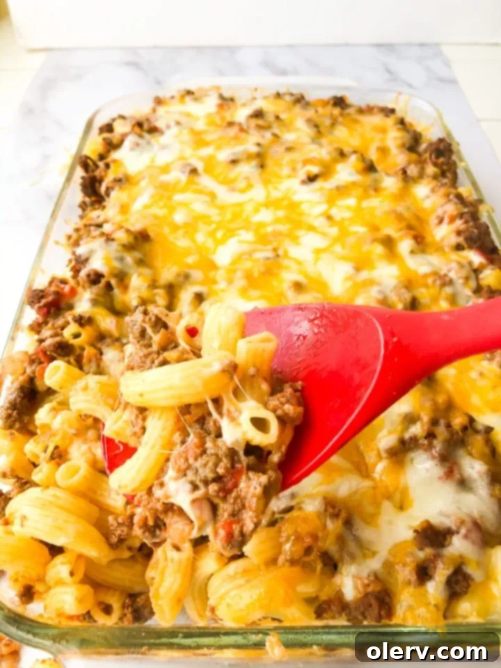 Decadent Loaded Mac & Cheese Bake 4 A dish of Loaded Mac and Cheese Casserole, ready to be served, with a spoon taking a portion.