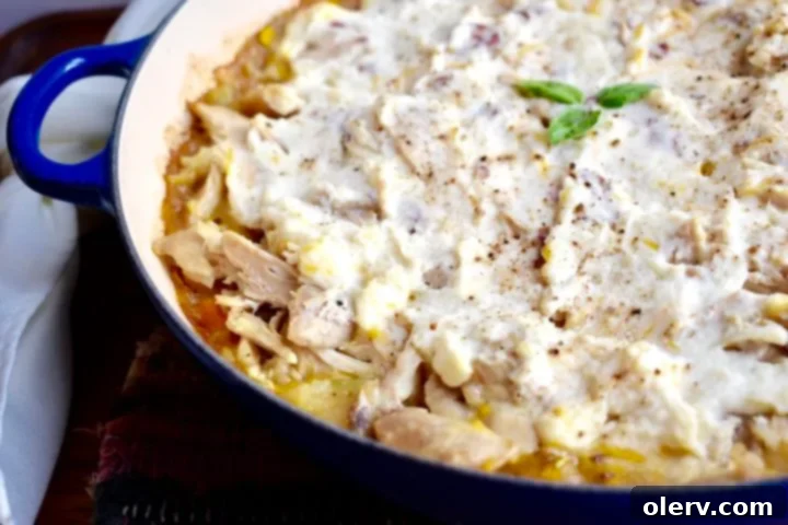 Creamy Chicken & Potato Bake 4 A close-up shot of shredded cooked chicken, corn, and mixed vegetables simmering in a savory sauce within a skillet, ready for the mashed potato topping.