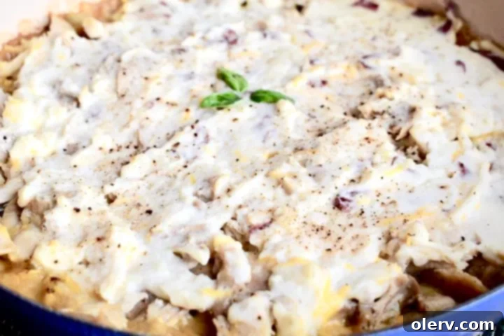 Creamy Chicken & Potato Bake 5 Creamy mashed potatoes being spread over the chicken and vegetable filling in a skillet, creating the signature top layer of the shepherd's pie.