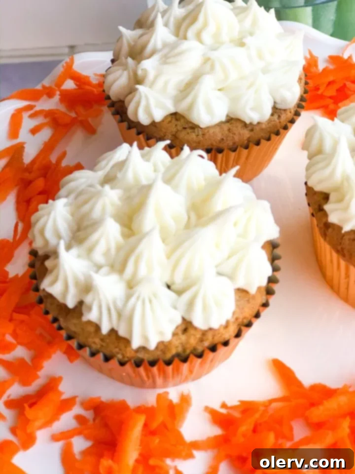 Spiced Carrot Cupcakes with Silky Cream Cheese Frosting 3 Close-up of a single Carrot Cake Cupcake, showcasing the fluffy cream cheese frosting and moist cake base.