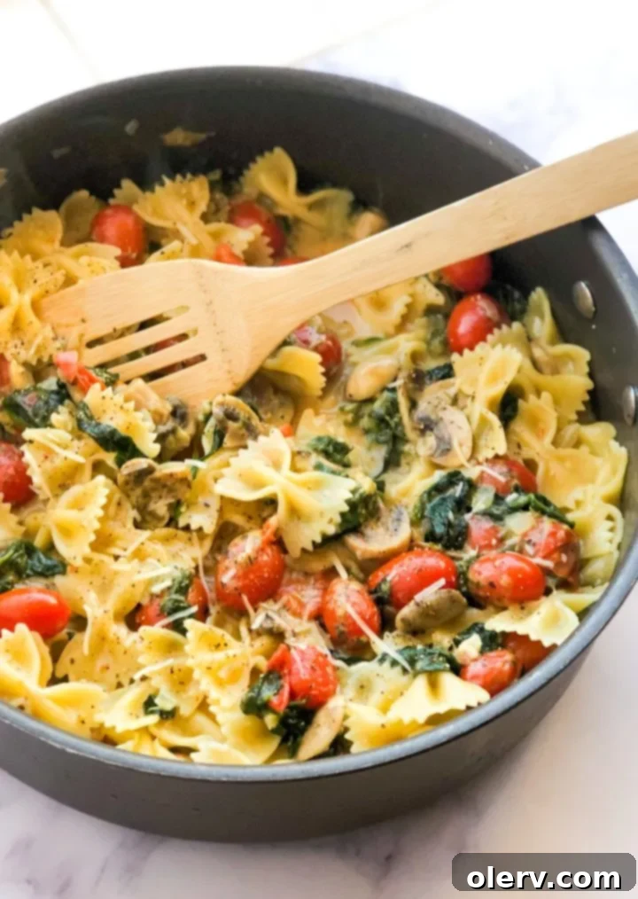 Delicious Meatless Mushroom Spinach Pasta 7 A generous serving of Mushroom Spinach Pasta in a large white bowl, garnished with fresh basil leaves
