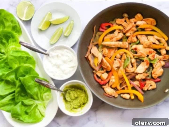 Low-Carb Chicken Fajita Lettuce Wraps 2 Freshly prepared lettuce wrapped chicken fajitas ready to be served on a platter.