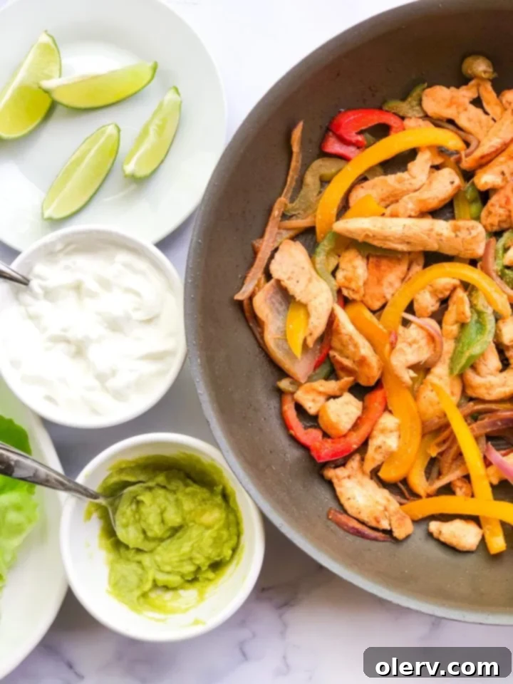 Low-Carb Chicken Fajita Lettuce Wraps 4 A plate of two lettuce wrapped chicken fajitas, garnished with fresh lime wedges and cilantro.