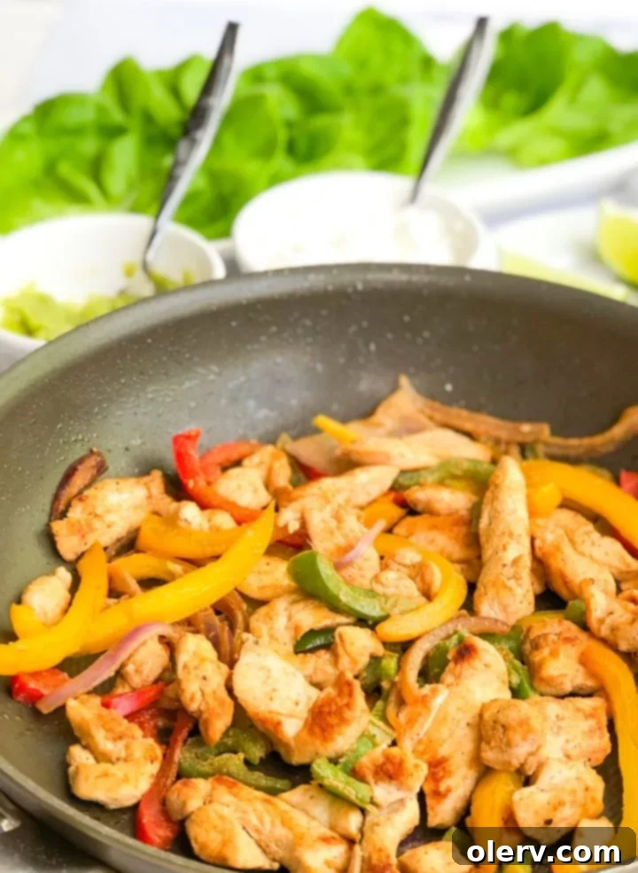 Low-Carb Chicken Fajita Lettuce Wraps 6 Hand holding a perfectly crafted lettuce wrapped chicken fajita.
