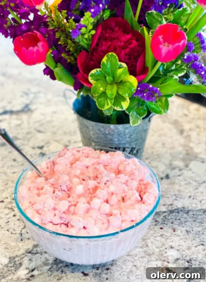 Cherry Cloud Delight 7 Cherry Fluff Salad served in a large glass bowl, with a serving spoon, and a small portion in a white ramekin, garnished with fresh mint.
