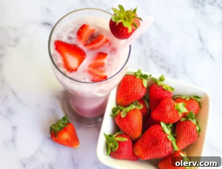 Homemade Pink Drink 2 Homemade Starbucks Pink Drink in a clear glass with sliced strawberries
