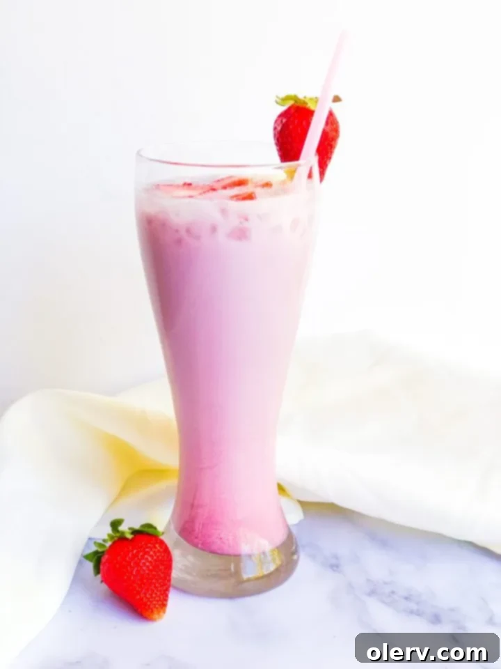 Homemade Pink Drink 4 A glass of Pink Drink with a straw and fresh strawberries