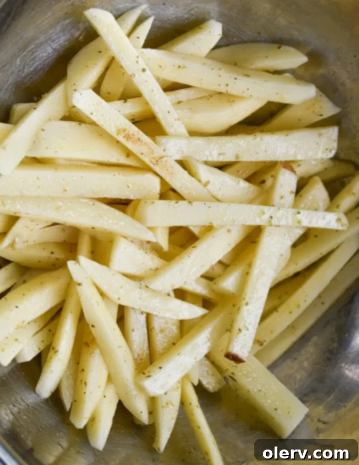 Mouthwatering Seasoned French Fries 7 Potatoes being tossed with seasoning and oil in a bowl