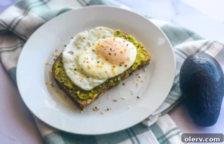 Savory Avocado Egg Toast 6 Two slices of fried egg avocado toast on a rustic wooden board.