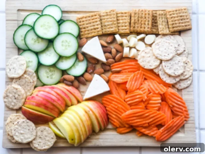 Effortless Summer Bites 2 A beautifully arranged summer snack board featuring fresh fruits, vegetables, cheeses, and crackers, ideal for healthy snacking.