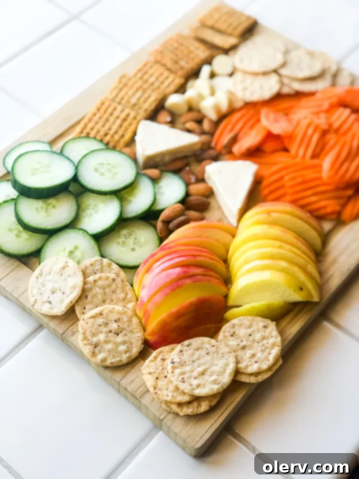 Effortless Summer Bites 7 A top-down view of a completed healthy summer snack board, showcasing a colorful array of fruits, vegetables, crackers, and cheese.