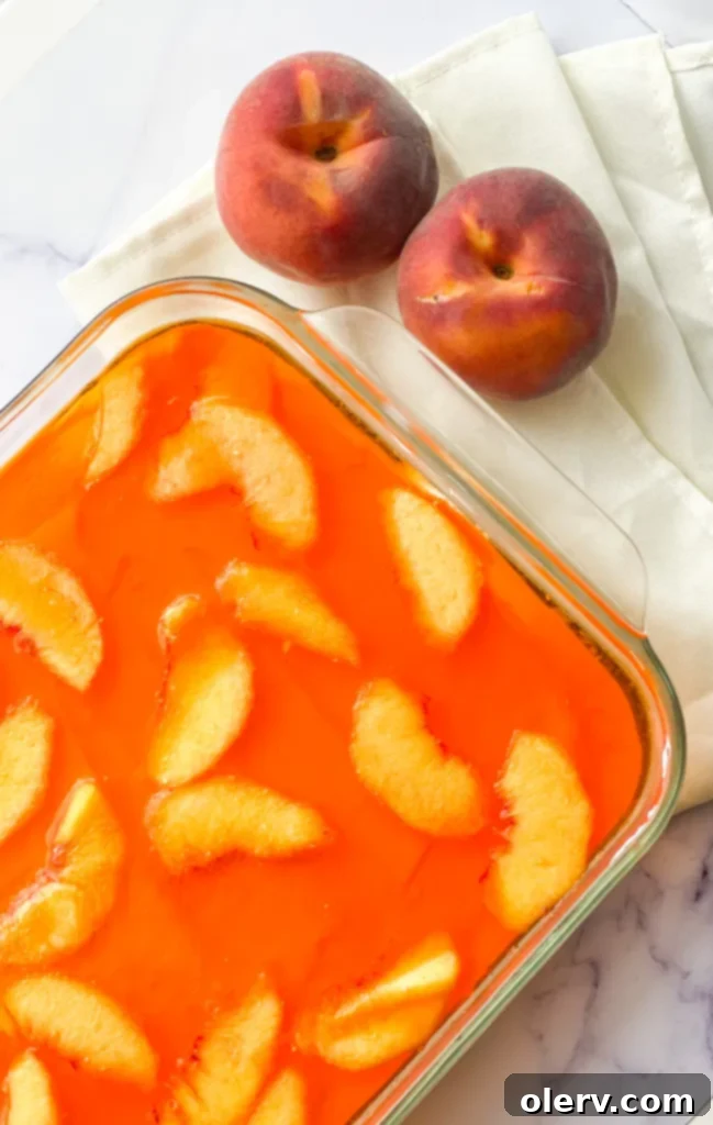 Overhead shot of a large pan of Peaches & Cream Pretzel Salad, with several slices already removed.