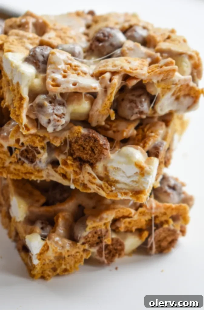 S'mores Cereal Bars 6 Freshly made S'mores Cereal Bars cooling in a pan, with a piece lifted, showing the gooey texture.