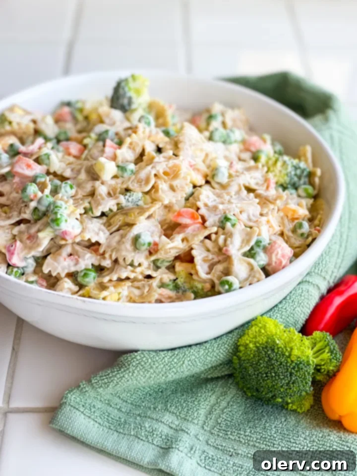 Velvety Farfalle Pasta Salad 5 A large bowl of Creamy Bow Tie Pasta Salad, ready to be served, with a spoon in the bowl.