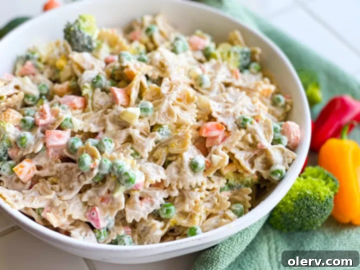 Velvety Farfalle Pasta Salad 6 A wide shot of Creamy Bow Tie Pasta Salad in a large glass bowl, garnished with fresh herbs, ready for a gathering.