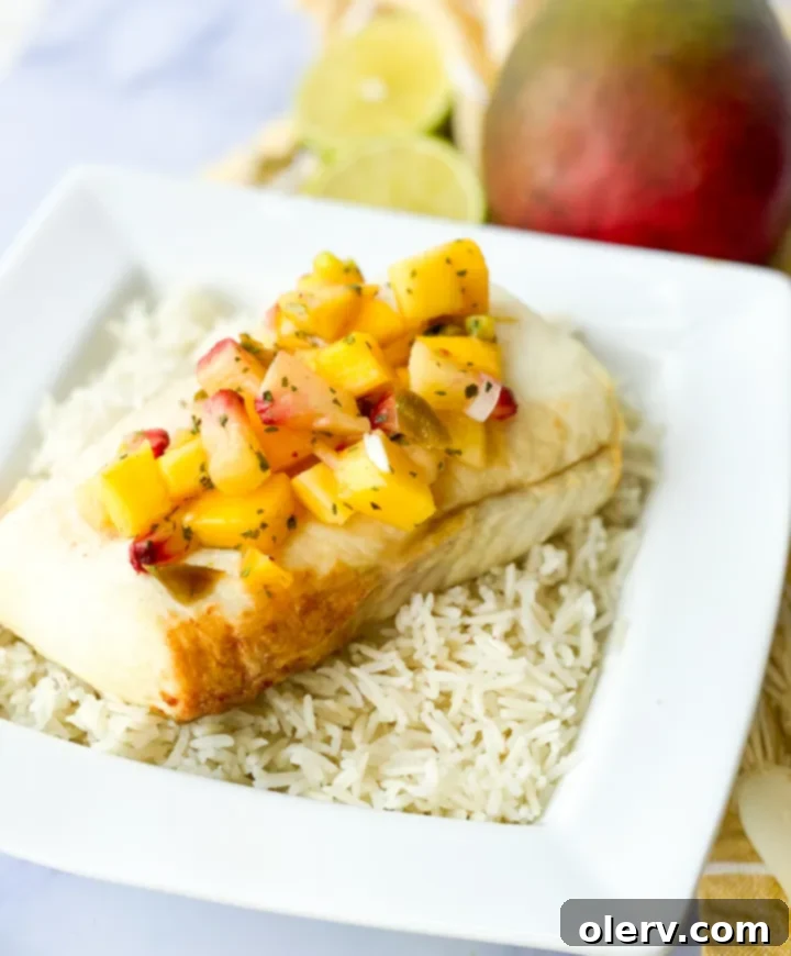Flaky Air Fryer Halibut with Zesty Mango Salsa 3 Closeup of perfectly cooked air fryer halibut fillet topped with colorful mango salsa.