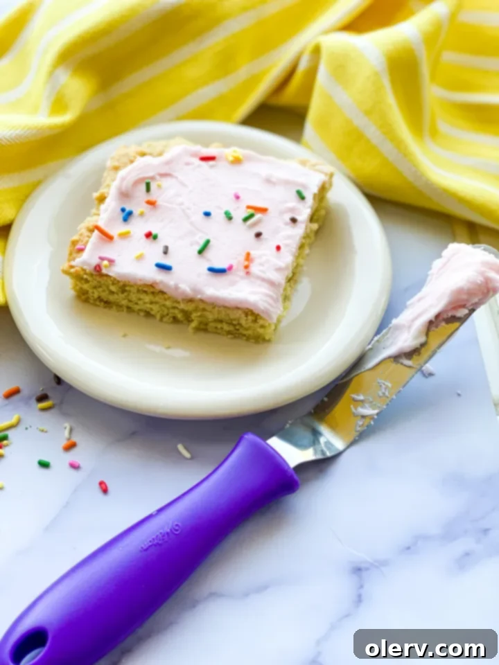 Heavenly Frosted Sugar Cookie Bars 5 A hand holding a frosted sugar cookie bar, ready to take a bite, highlighting its tempting layers.