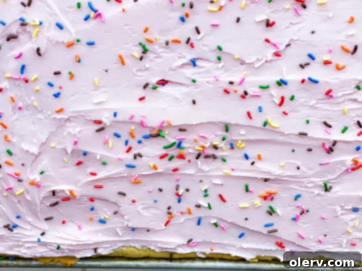Heavenly Frosted Sugar Cookie Bars 6 A close-up of several Frosted Sugar Cookie Bars on a white plate, highlighting their perfect frosting and sprinkles.