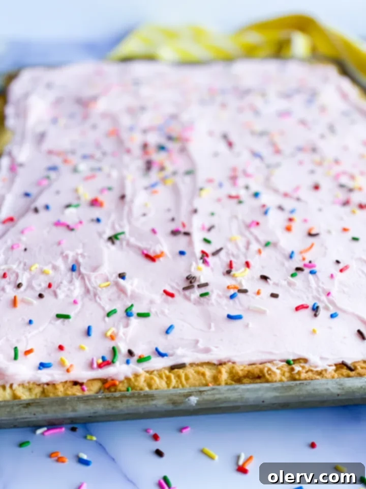 Heavenly Frosted Sugar Cookie Bars 7 A top-down view of Frosted Sugar Cookie Bars on a cutting board, garnished with sprinkles.