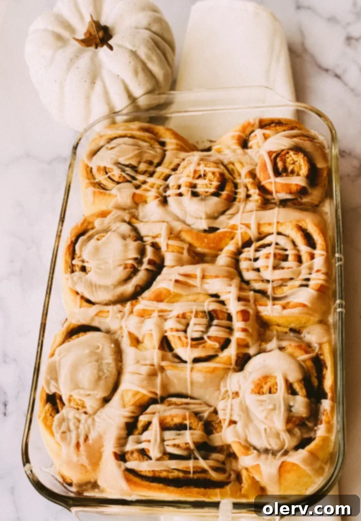 Spiced Pumpkin Cinnamon Rolls with Brown Butter Glaze 7 Close-up of brown butter glaze being drizzled on cinnamon rolls