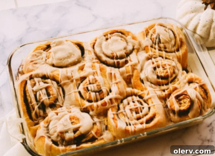 Spiced Pumpkin Cinnamon Rolls with Brown Butter Glaze 8 Close-up of a single pumpkin cinnamon roll with glaze