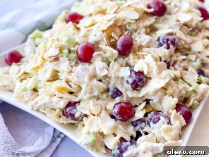 Tropical Sweet Pineapple Pasta Salad 2 A vibrant bowl of Sweet Pineapple Pasta Salad, featuring perfectly cooked bowtie pasta, juicy pineapple chunks, red grapes, and tender chicken, all coated in a rich, creamy sauce.